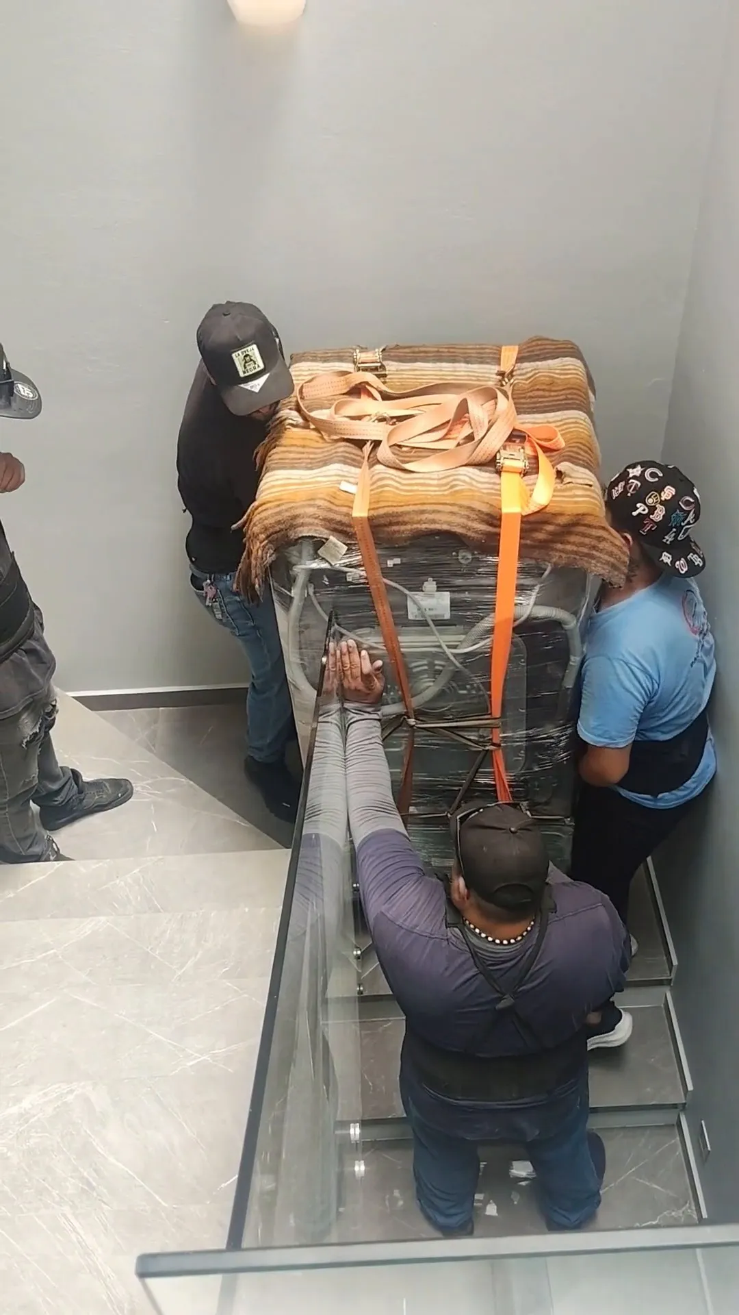 Cuatro integrantes subiendo una carga con bandas por el cubo de la escalera